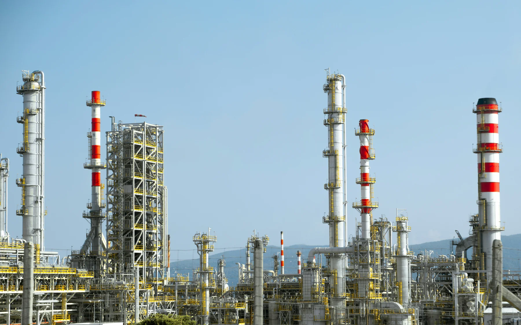Silver refinery processing towers and pipework beneath a clear blue sky