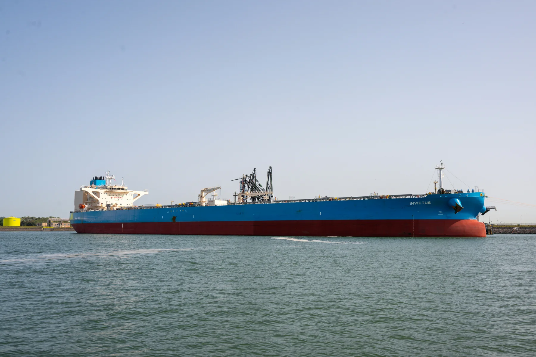 Blue and red oil tanker moored at a harbor terminal